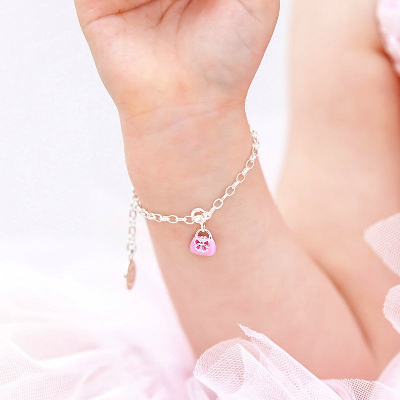 Young Girl wearing Children's Charm Bracelet in Sterling Silver with Two-Toned Pink Enamel Handbag Charm